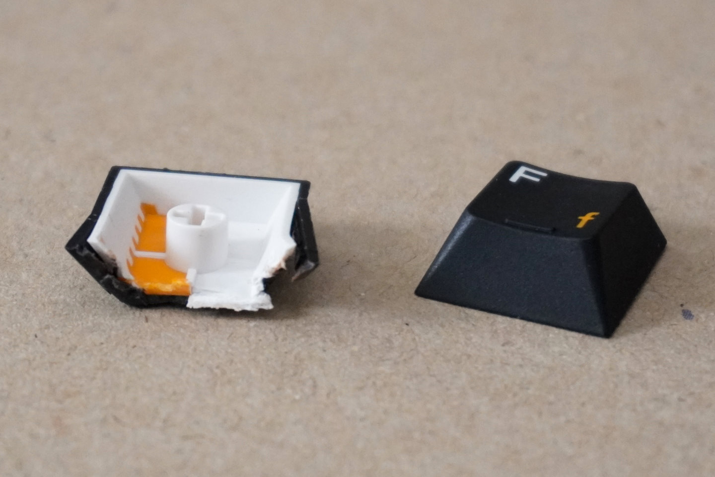 將三色成形PBT鍵帽切開，可以從剖面看到，黑、白、橘3種色塑料如何共。