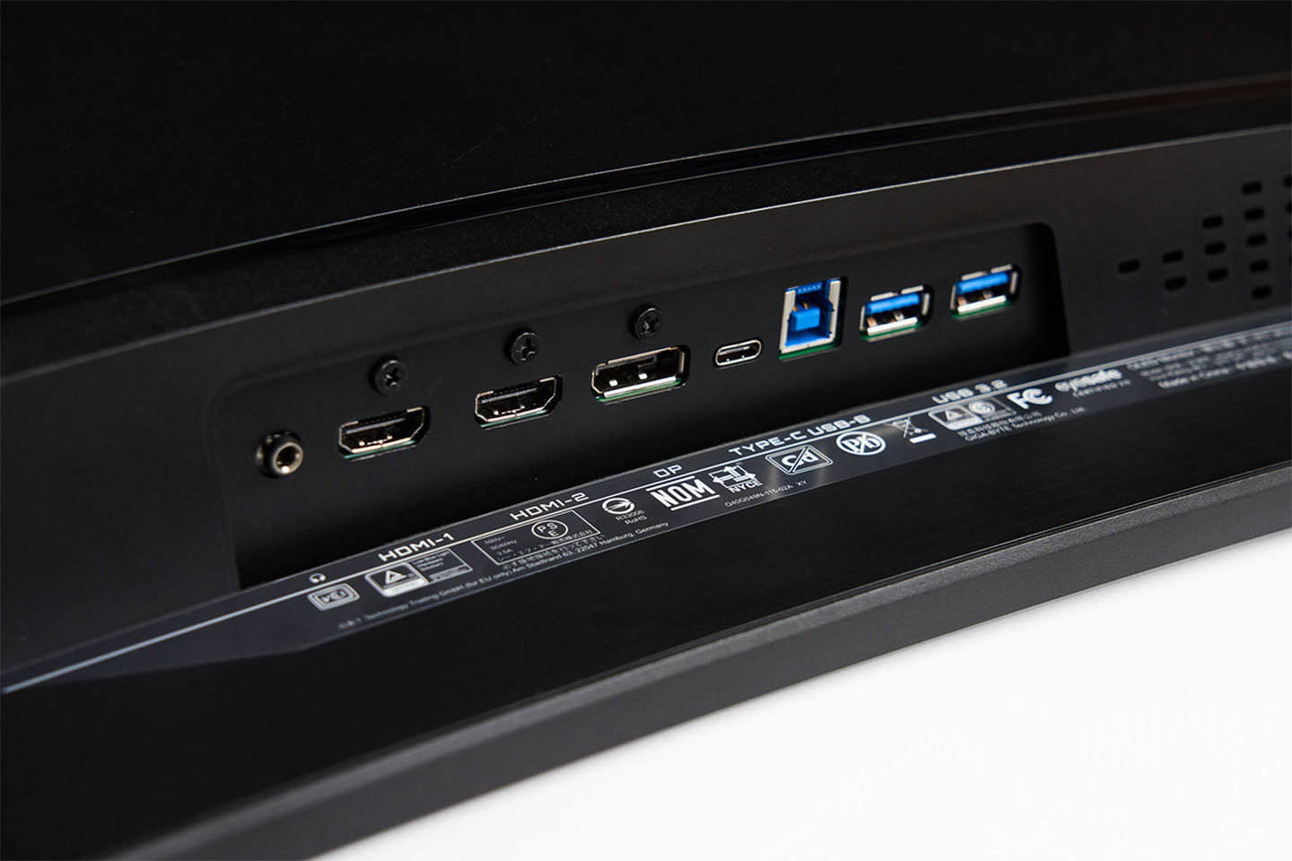 連結埠同樣置於底側，左至右分別為 3.5 mm 音源輸出、HDMI 2.1 兩組、DP 1.4 一組、USB-C 一組、USB-B 一組（連結電腦擴充用）、兩組 USB 3.2 埠可連結鍵盤、滑鼠支援 KVM 功能。